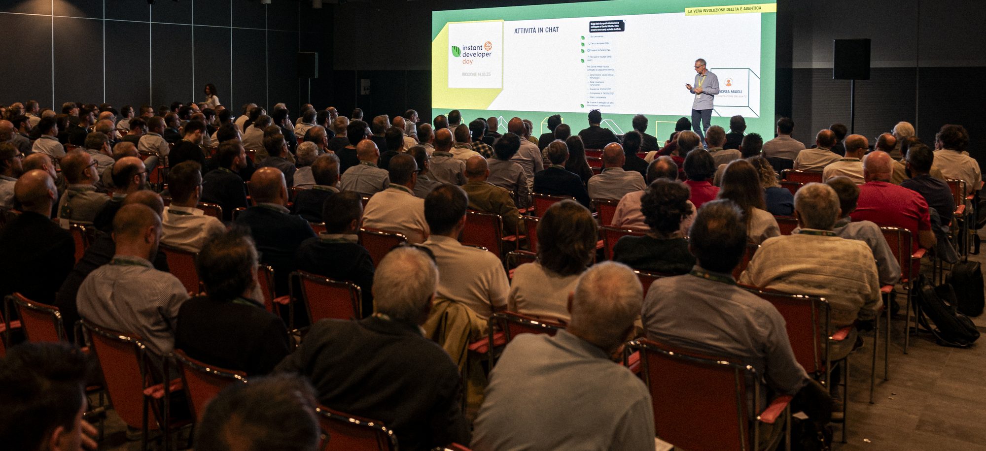 Sala piena all'Instant Developer Day di Riccione: il pubblico di spalle, sul palco Andrea Maioli davanti alla slide «La vera rivoluzione dell'IA e agentica».